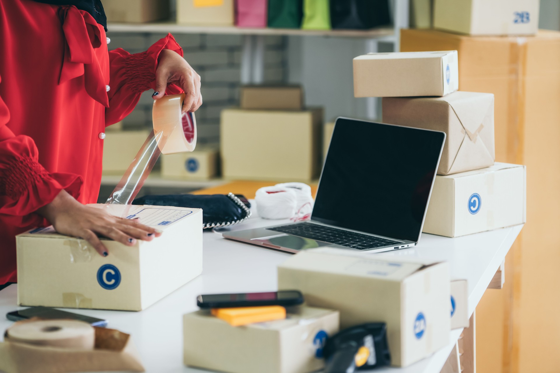 Online seller works at home office and packs shipping delivery box to customer.